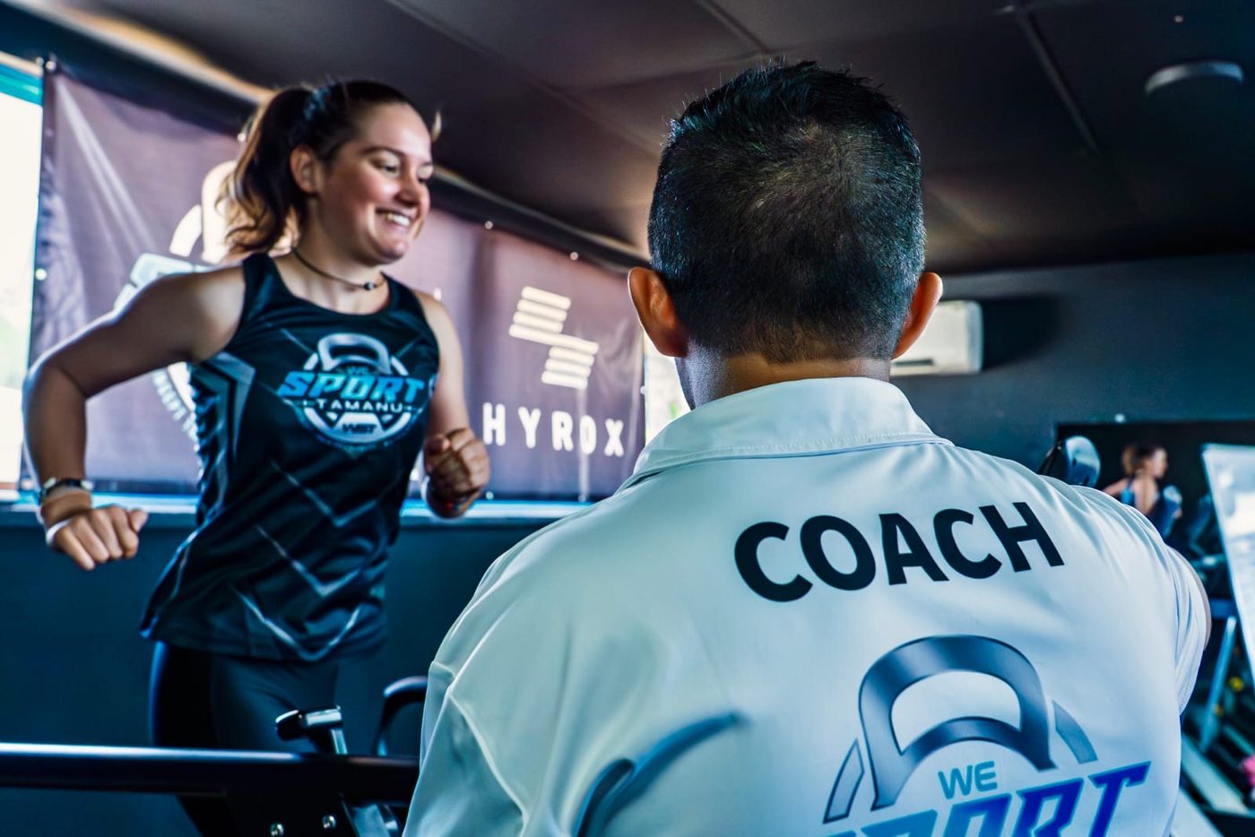 Un coach WeSport encourage une cliente qui court sur le tapis de la salle
